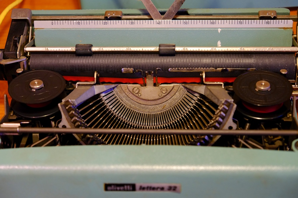 Above: Type basket exposed. Note the ribbon and spools (which required an automatic reversing mechanism), the platen roller and the pica scales