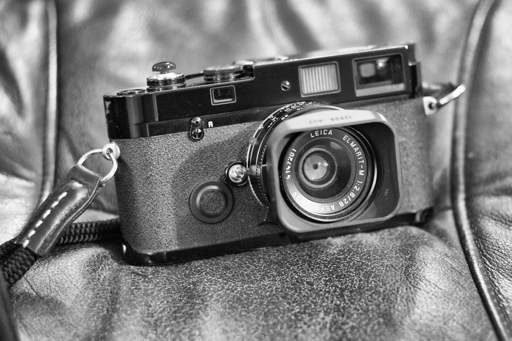 Nearly ten and a bonny baby at that. Note the paint rubbing off around the lugs and in one or two other places you cannot see. Most people will pay extra for that. Here it is with a 28mm f/2.8 Elmarit lens. Â Below you can see my mods: a Tim Isaac red bug shutter release button and an old Thumbs Up made for the Leica M9 and which sort of fits securely. The strap is an Artist & Artisan silk strap in the long (over the shoulder) version. Photos Mike Evans, Leica M with 50mm Summilux: f/4 @ 1/30s, ISO 3200, very low light conditions