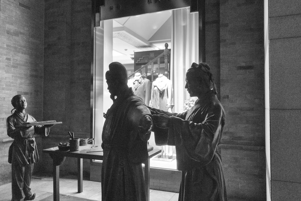 Clothes ancient and modern: In Qianmen Avenue south of Tiananmen Square. ISO 1250, 28mm taken at f/3.5, 1/60s. B&W in Silver Efex Pro