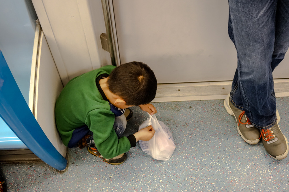 Metro trains are invariably crowded but this little chap managed to find himself his own tiny space, happily playing with the plastic bag. What was inside? Condoms!