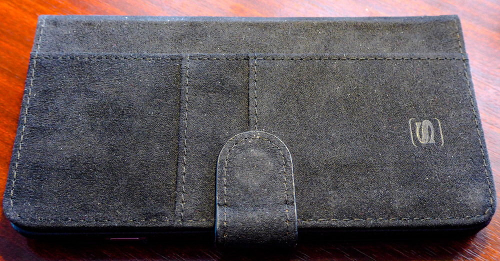 The cover folds back out of the way when holding the phone. It adds to stability and the closure flap attaches neatly to the inside of the cover by magnets