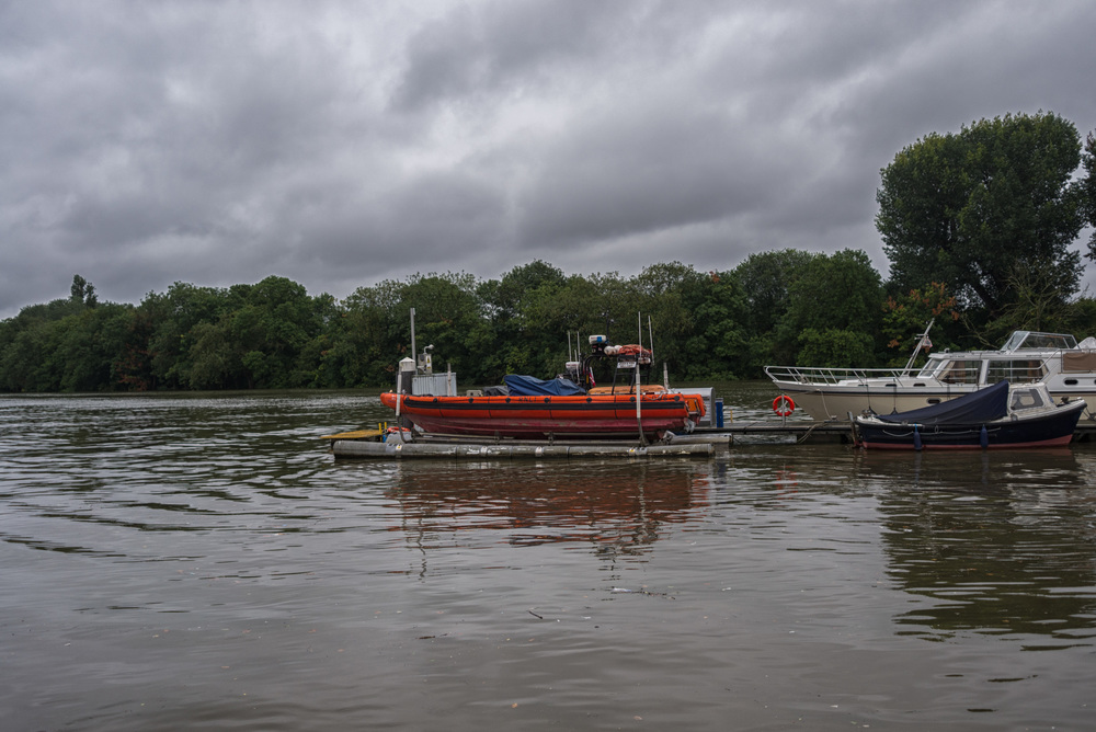 Chiswick life boat rides high as the Thames tide approaches record levels. On calmer and less gloomy days, as below, the Royal National Lifeboat Institute rescue vessel rides low on its moorings. Note the top of the pole almost level with the boat in the above picture