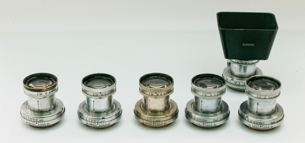 This is my collection of 5 different variants of the collapsible 5cm f2 Summar. Van Hasbrouck lists seven variants of the collapsible model. These ones include a black top chrome model, a nickel model and the remainder are chrome models with variations involving a notch at the f/2.9 mark for use with a filter for early Agfacolor film as well as models with and without ‘infra red’ marks. There are also metre and feet scale variations. The eagle eyed will have spotted a sixth Summar behind. This is not another variant but it seems to be a reconstructed model using the mount of one variant (front second right) and the front element of another variant ( front second left). Hence, I have just used this one to ‘model’ the SOOMP (Leica New York version) hood for the Summar. 