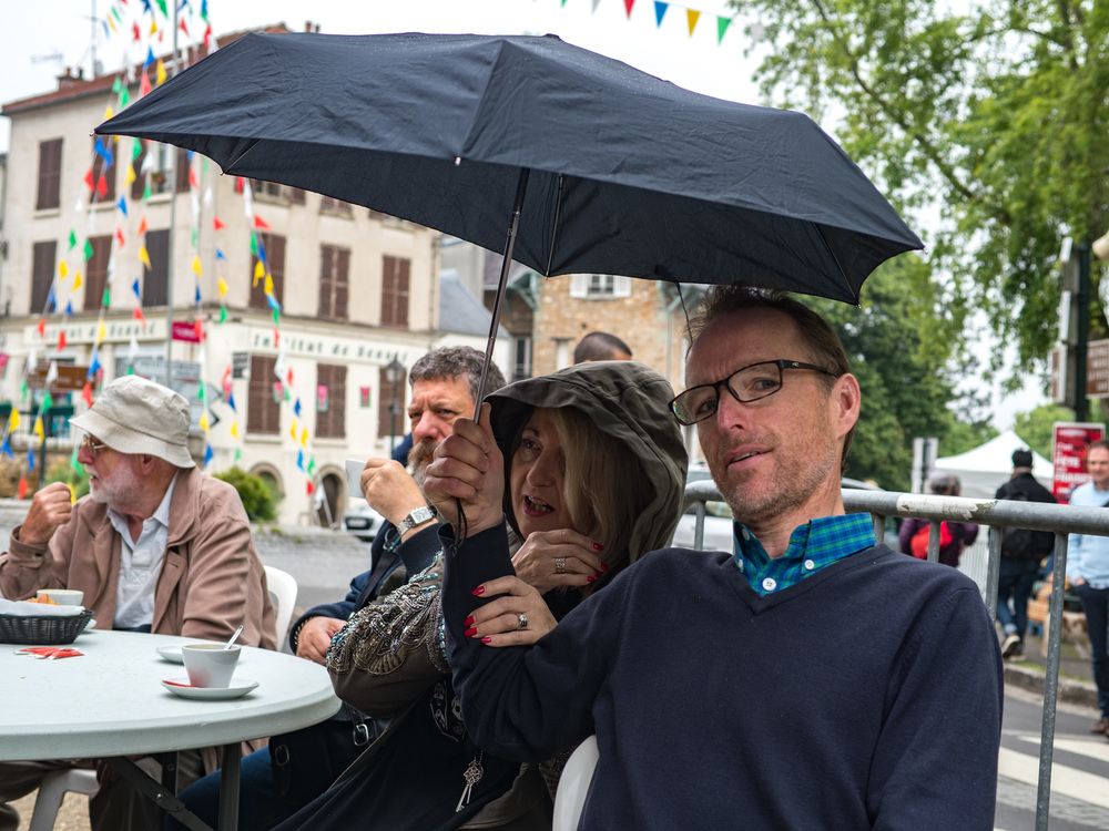 British dealer Peter Loy (right) shares an umbrella with Elaine Cooper of Red Dot Cameras. Ivor Cooper catches the drops next to Elaine