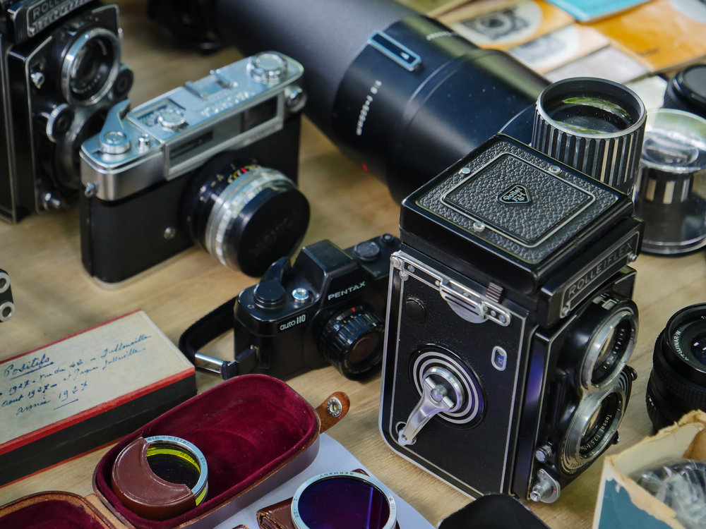   A dinkie little Pentax 110 single-lens reflex with interchangeable lenses (similar to the one Mike carried off back to England) lurks behind the big-brother twin-lens-reflex Rolleiflex  