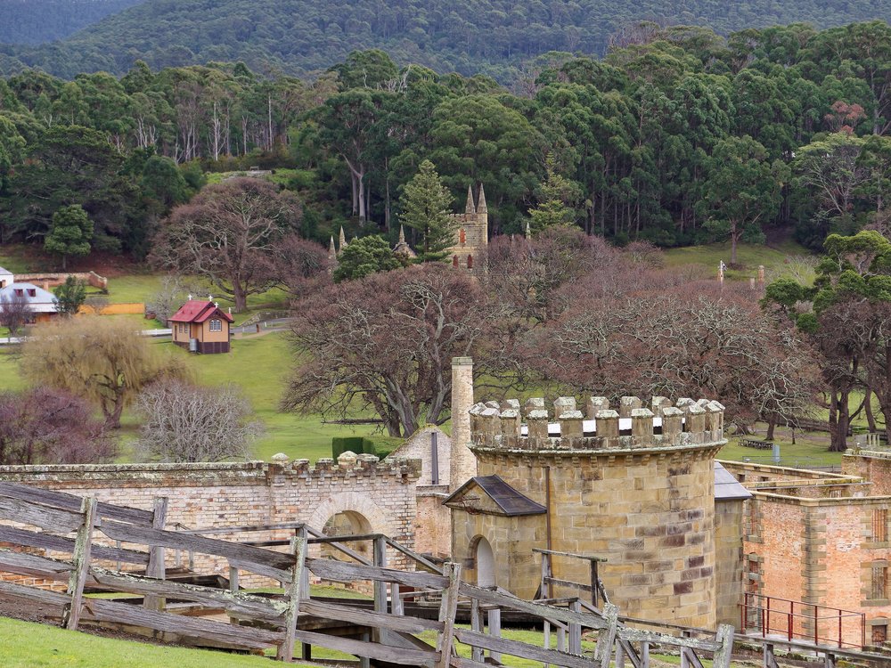 Looking across the Port Arthur Penal settlement. The original church spire ruins are glimpsed in the trees, the more recent St Davids Church (1927) in the clear ground to the left. One of the more notorious convict destinations early in the Australian colony, it is remote, savaged by weather and strangely beautiful