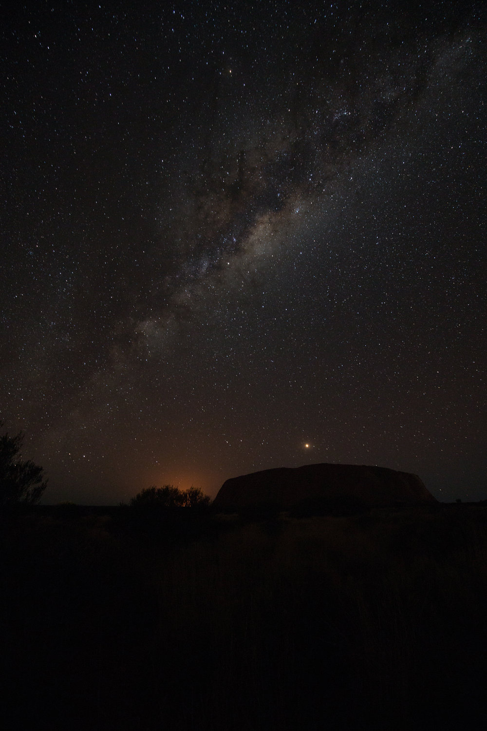 Uluru silhouetted against the Milky Way; the glow is the nearby Mutitjulu community, Canon 5D III and 16-35mm lens