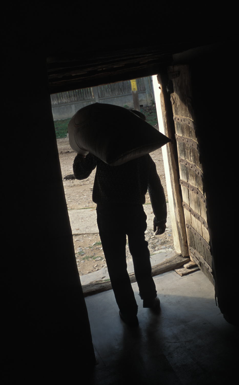 Man carrying sack of grain in The fortified church in Szekelyderz dariju village in Transylvania (Leica M6 and 35mm f/1.4 Summilux)