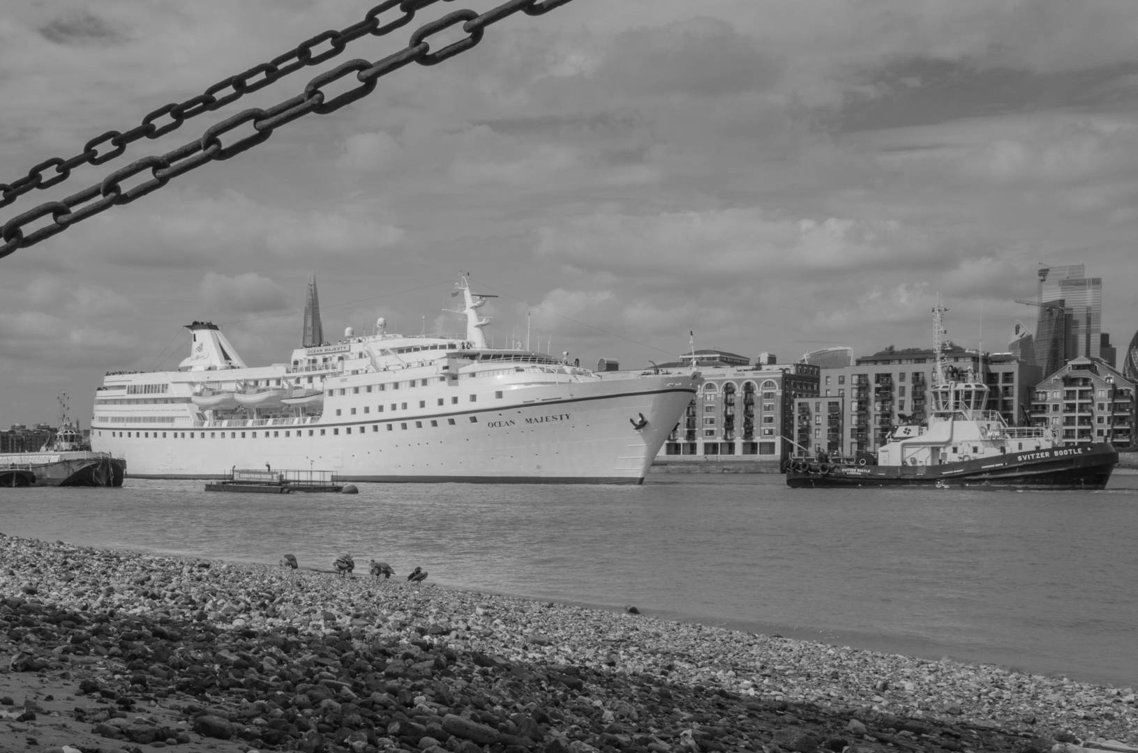 Tugs taking a cruise ship into the Pool of London. Facing the way out
