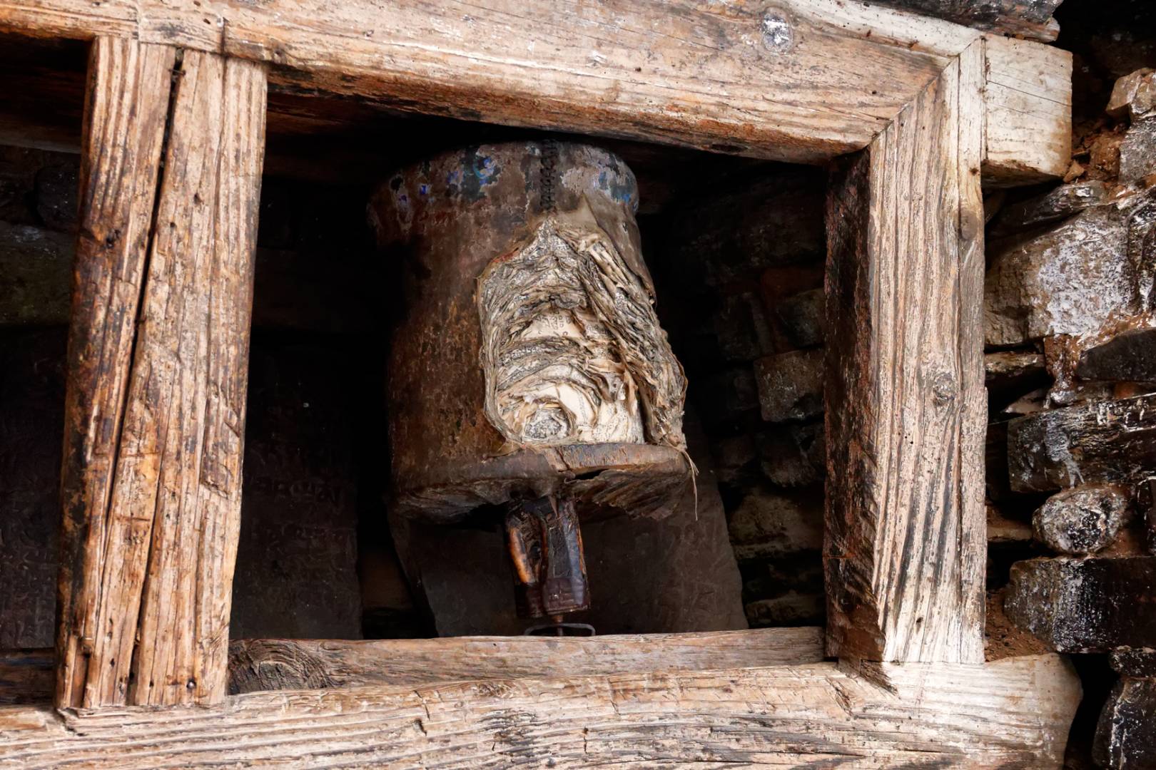 A weathered prayer wheel at the entrance