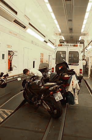 Interior view of a vehicle ferry with a motorcycle and a small bus parked inside, showcasing the unique transportation experience under the English Channel.