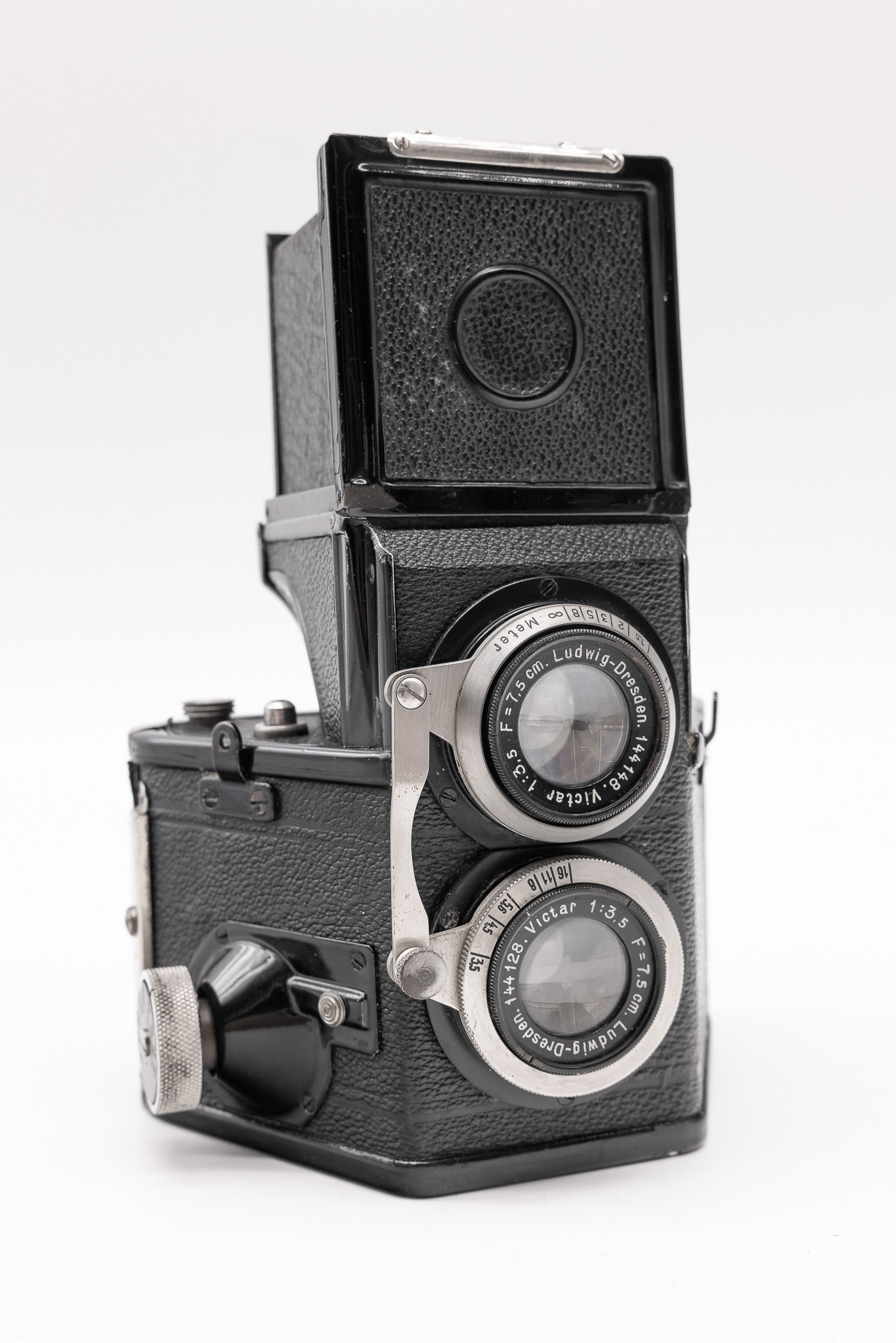 A vintage camera featuring a twin lens design, textured black leather body, and a distinctive viewfinder on top.