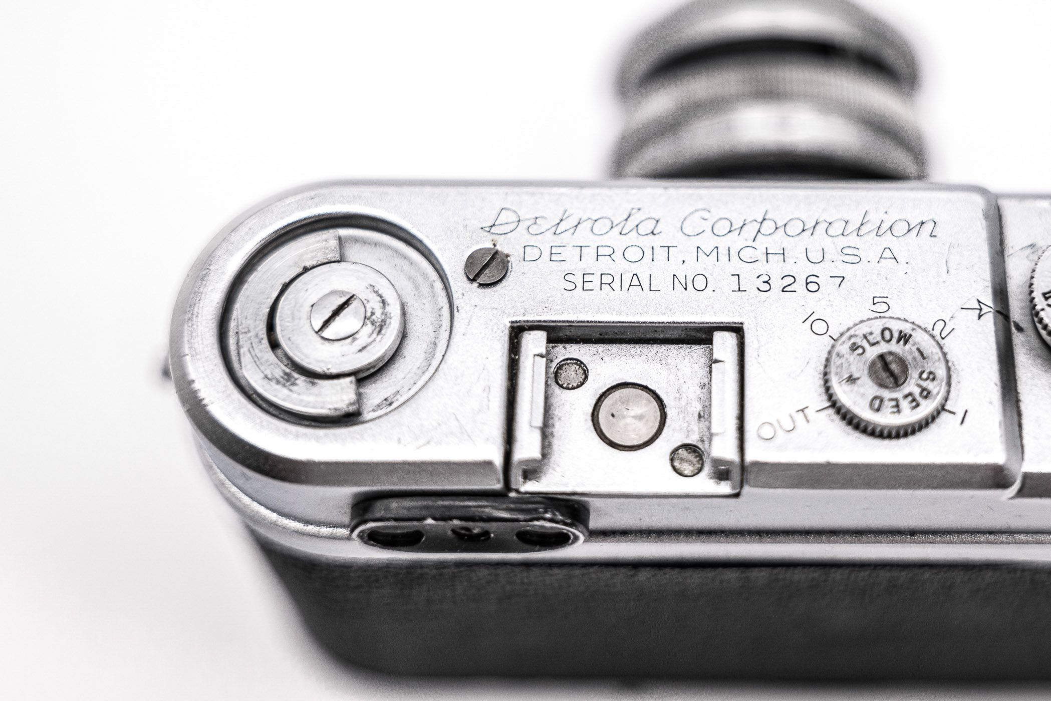 Close-up view of the top of a vintage Detrola camera, showing the brand name, serial number, and various dials and knobs.