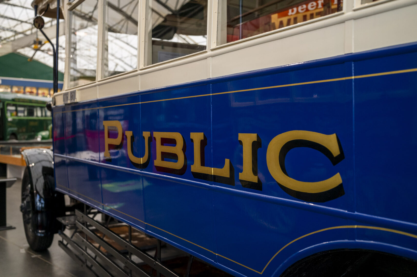 Side view of a vintage blue public transport vehicle, featuring the word 'PUBLIC' in bold gold lettering.
