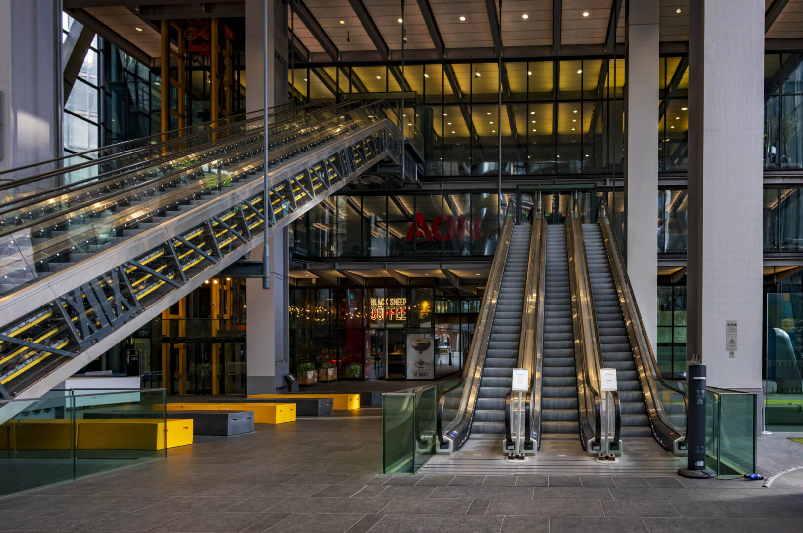Modern interior of a building featuring escalators, glass walls, and contemporary design elements.