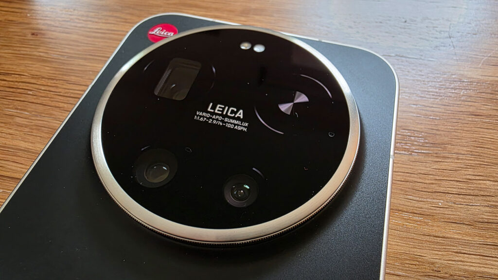 Close-up of a Leica camera lens featuring a circular design with three lens elements, a black surface, and engraved text detailing specifications.