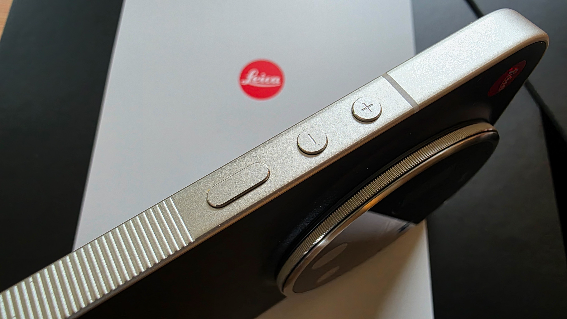 Close-up view of a Leica camera with control buttons, placed on a black and white background.