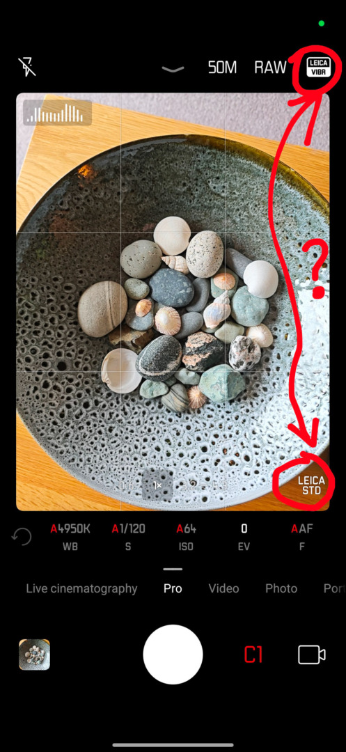 A close-up view of a bowl filled with various pebbles and stones, captured on a smartphone camera interface displaying settings like ISO and shutter speed.