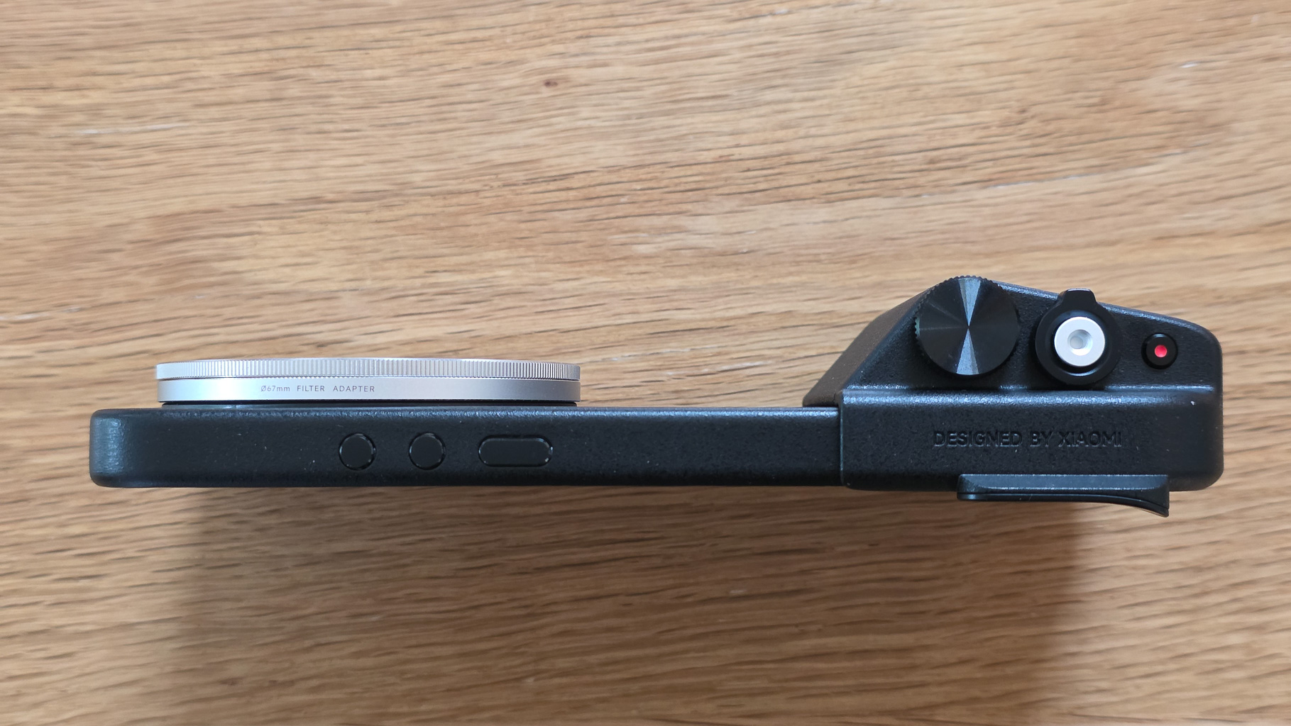 Side view of a black camera body with a silver filter adapter attached and various controls, including a knob and a button.