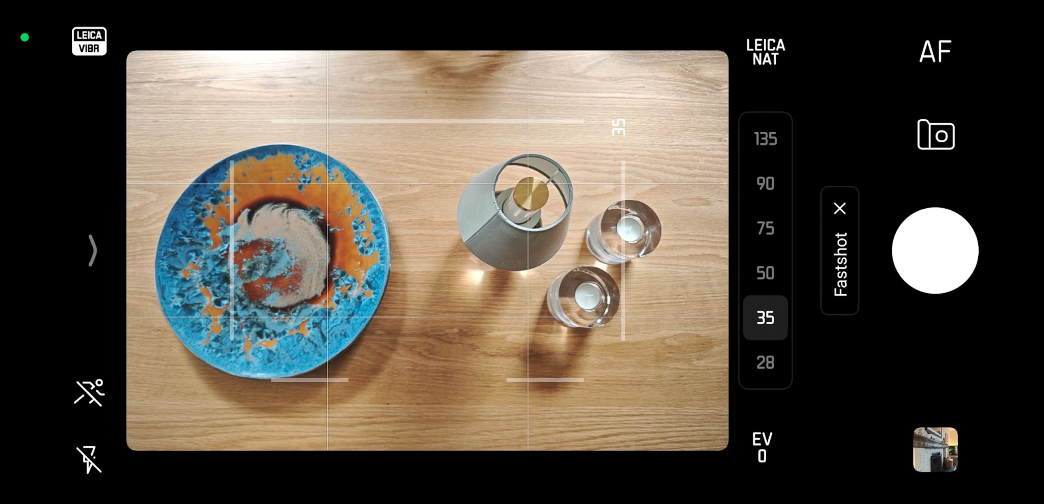 A blue and orange patterned plate with a dessert in the center, surrounded by two clear glasses and a metallic cup, set on a wooden surface, viewed from above.