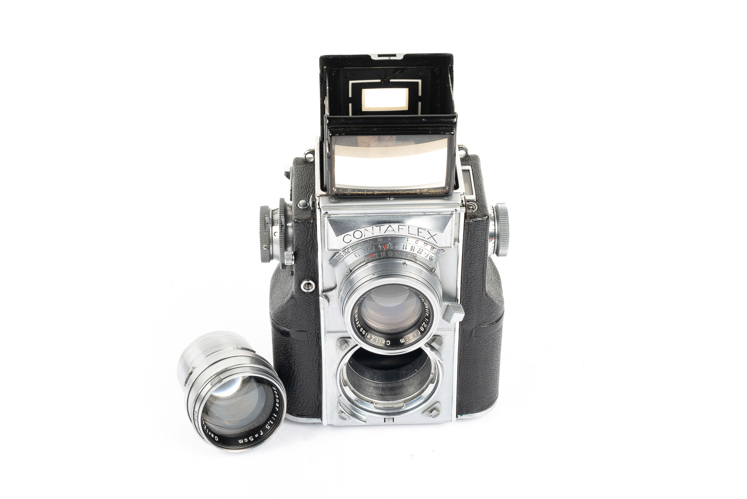 A vintage Contaflex camera with a hinged viewfinder, positioned upright, alongside a separate lens.