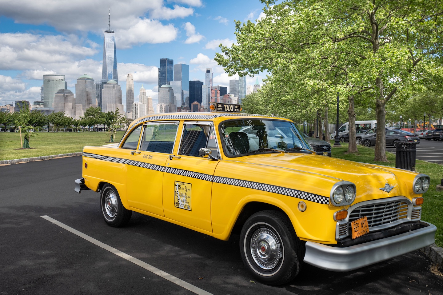Fifties-era yellow taxicab parked in front of skyline.