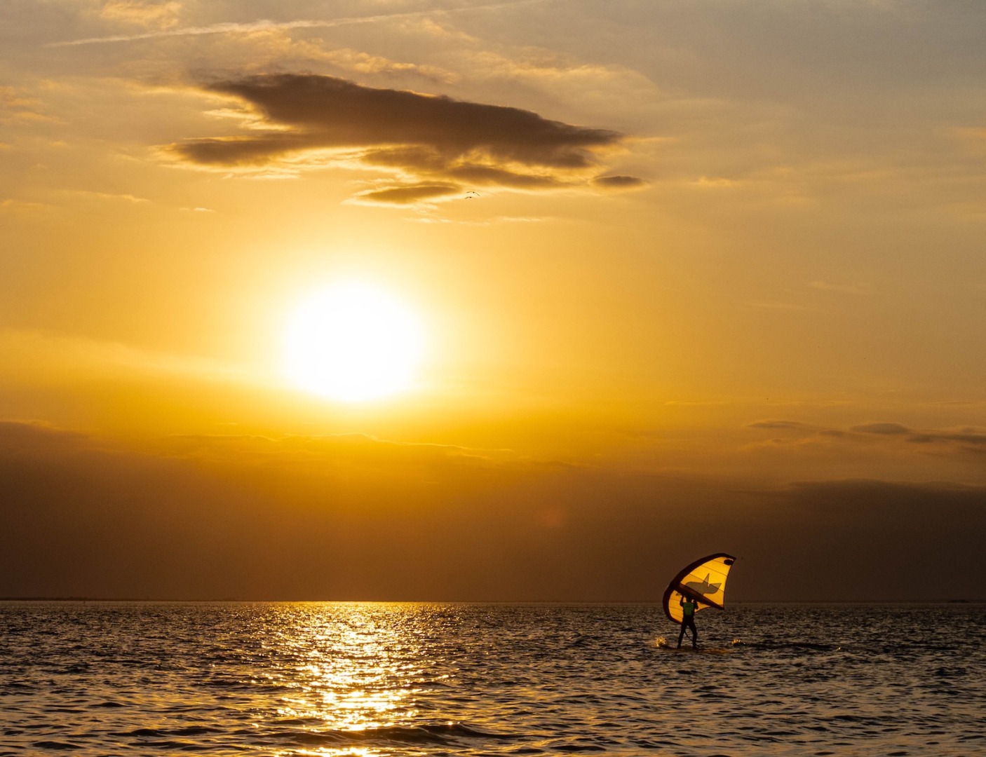 Wind-sail rider against a sunset sky.
