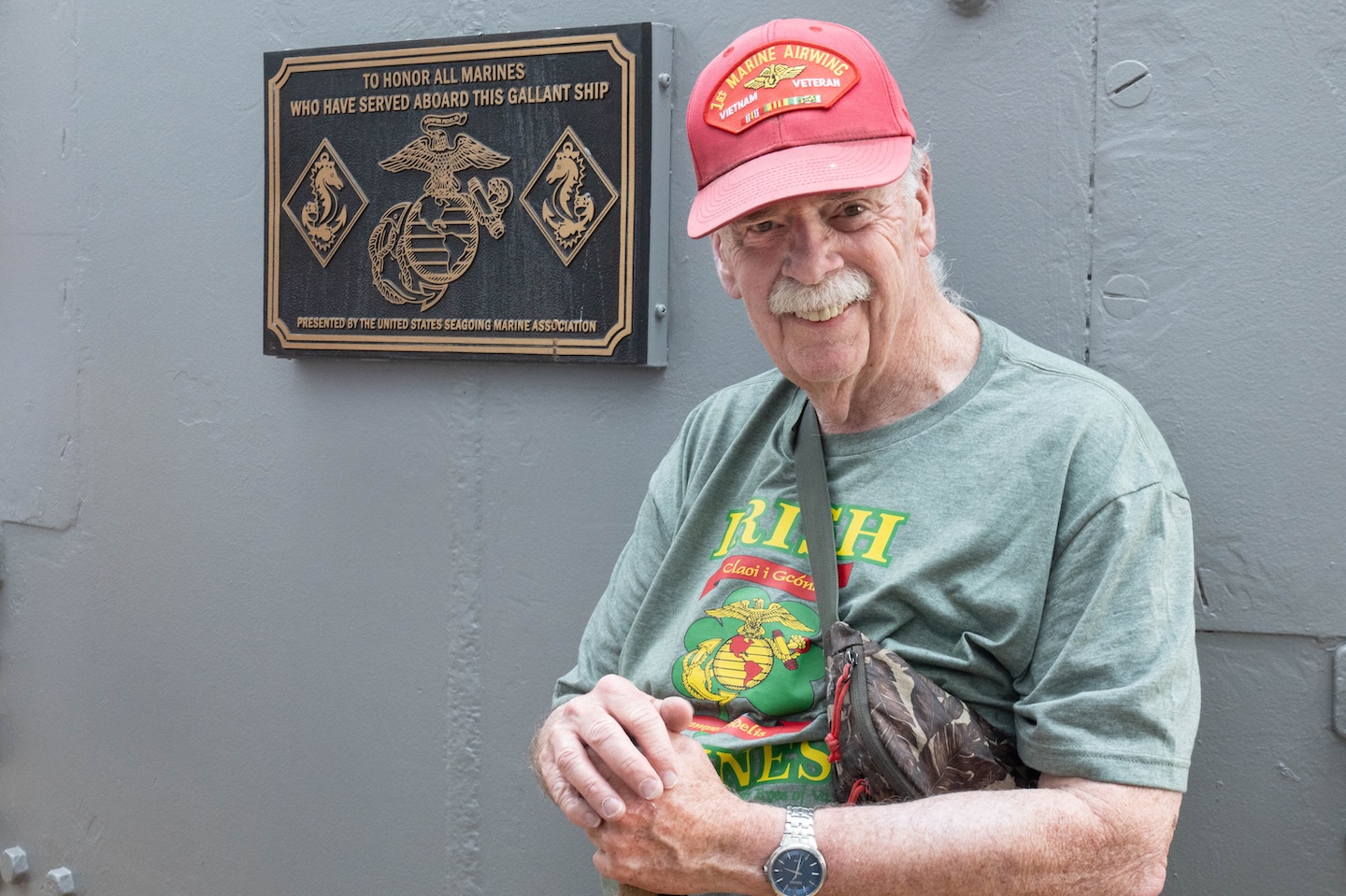 Man in red cap posed in front of a grey structure.