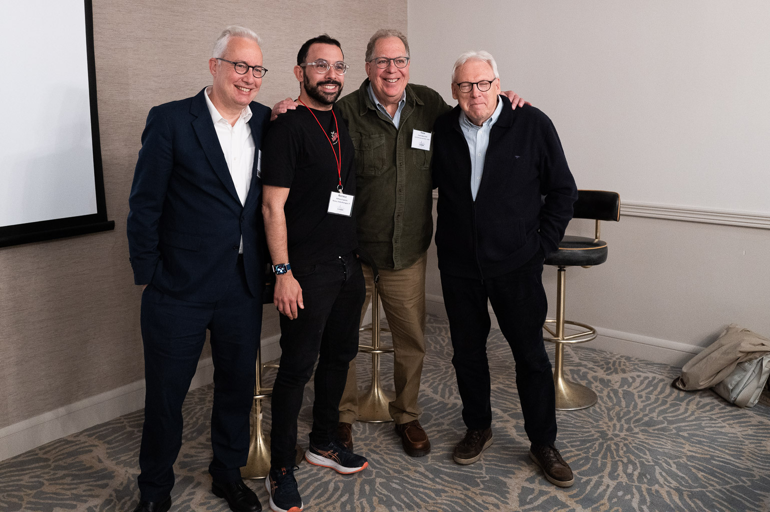 Four men posing together in a professional setting, smiling for the camera.