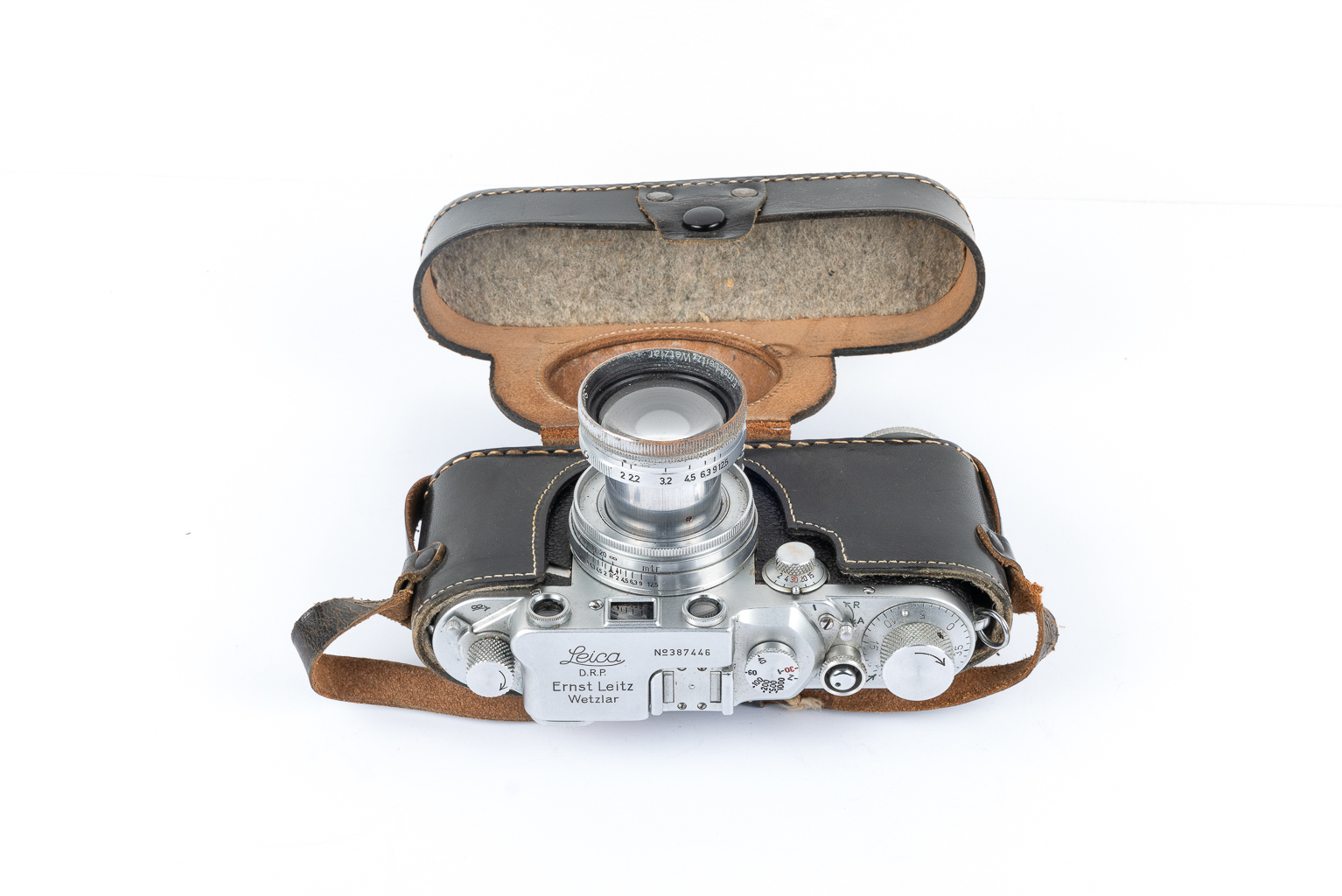 Vintage Leica camera in a brown leather case with the lid open, showcasing the lens and dials.