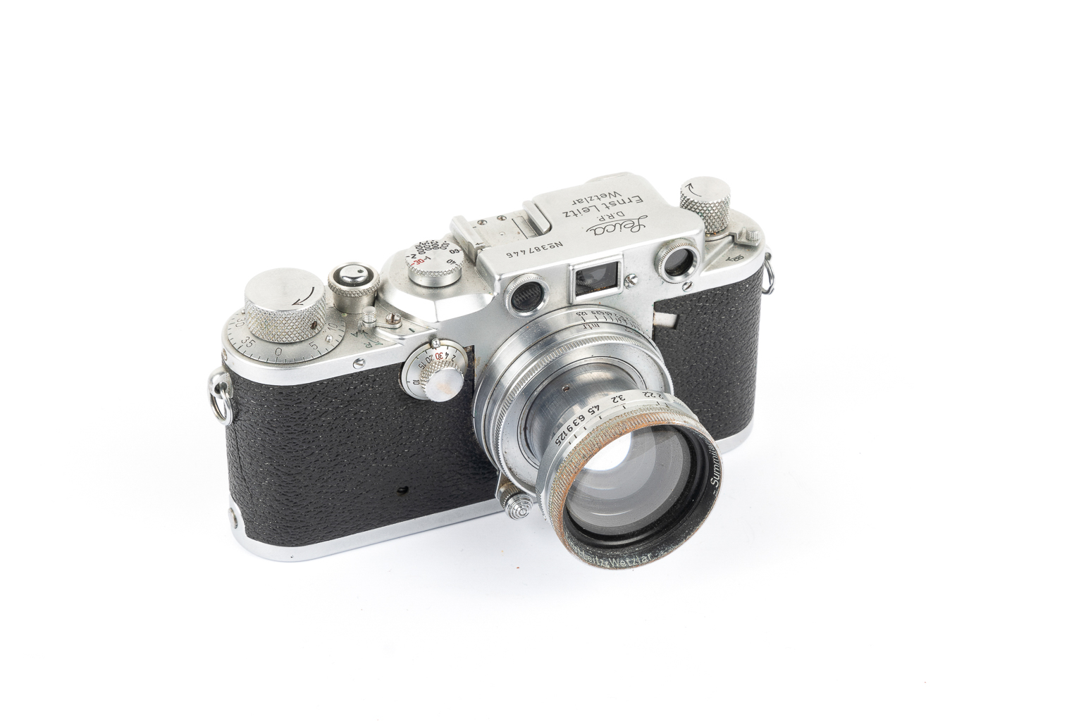 A vintage camera with a silver and black design, featuring a prominent lens and various dials on the top.