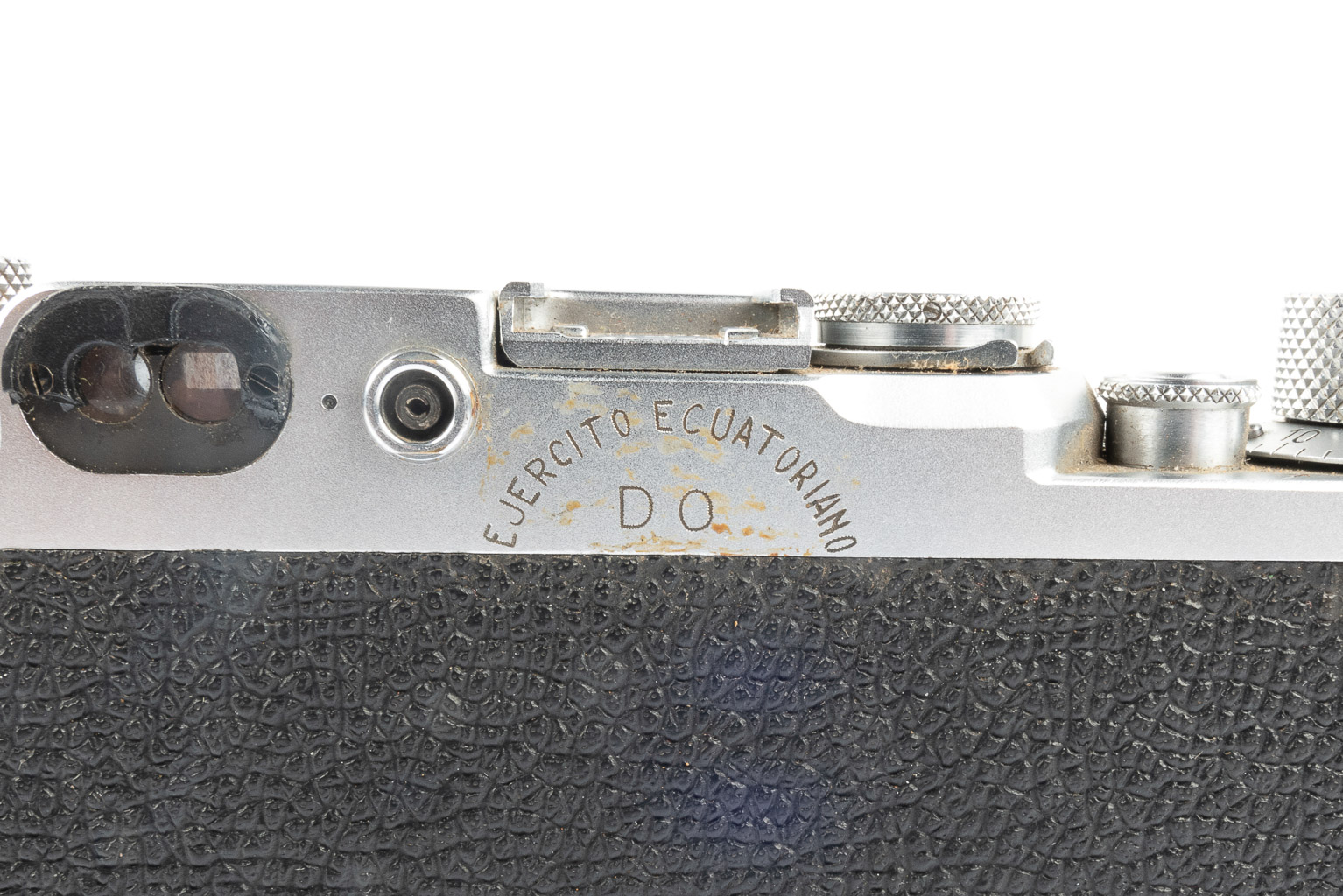 Close-up of an old camera detail showing the top with dials and engraved 'Ejercito Ecuatoriano' mark.