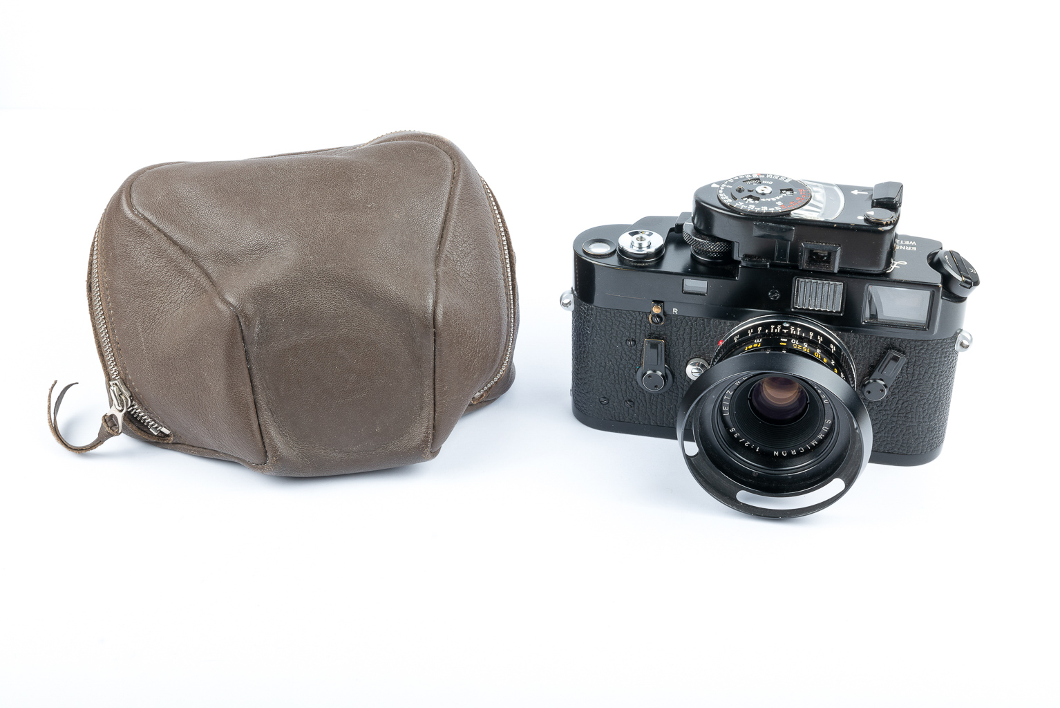 A vintage camera with a black body and a lens mounted on the front, positioned next to a brown leather camera case.