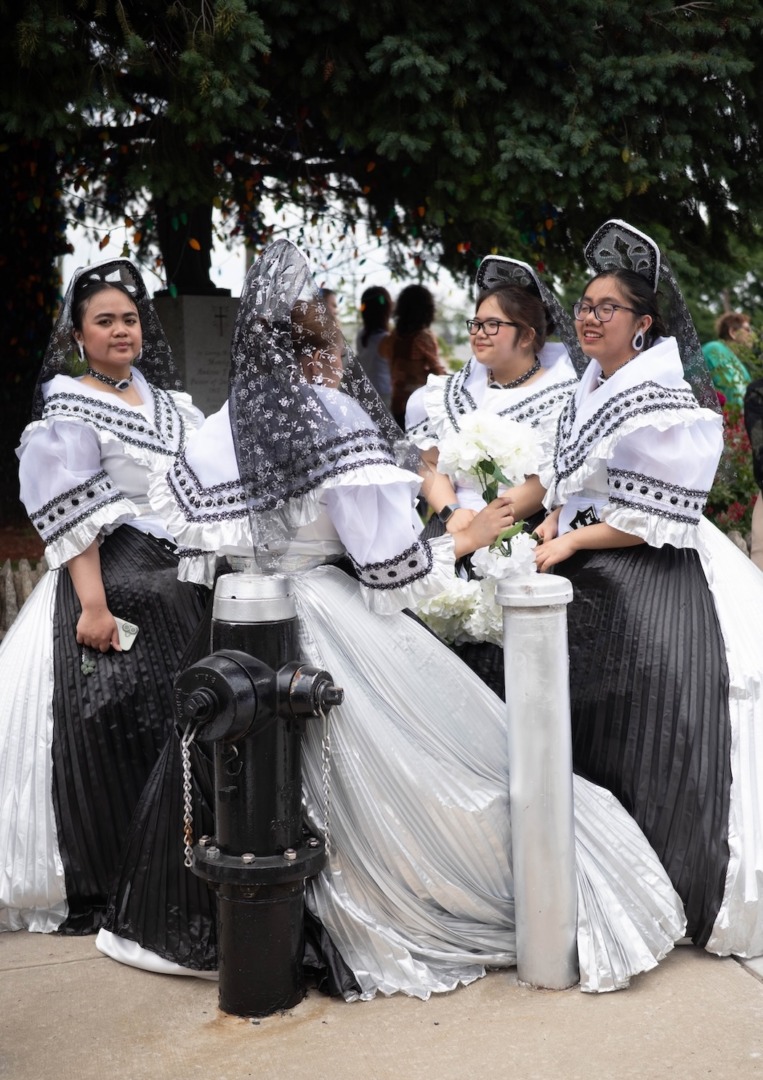 Women in white and black gowns standing next to fire hydrant.
