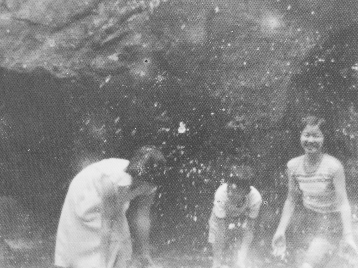 Three children playing and splashing water in a rocky outdoor setting.