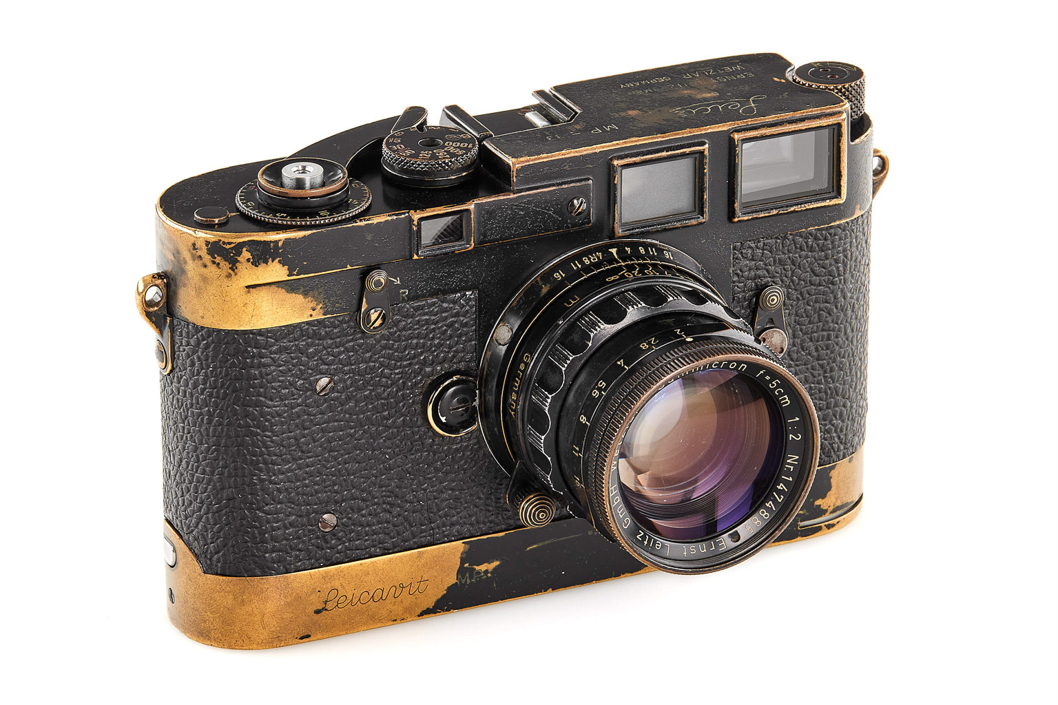 A vintage black and gold camera with a textured surface and a prominent lens, showcasing signs of wear and age.