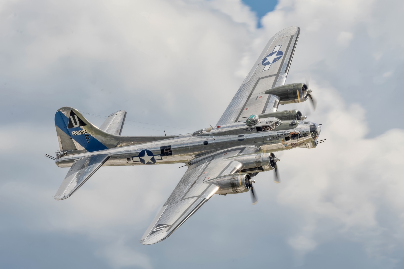 Second World War-era bomber flying in cloudy sky.