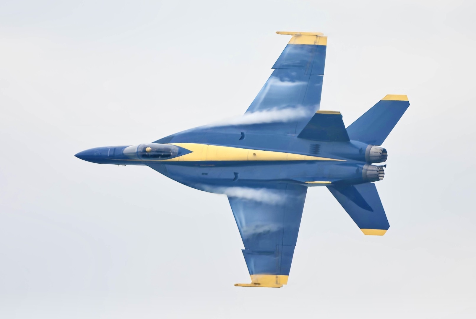 Blue an yellow fighter jet trailing white smoke.