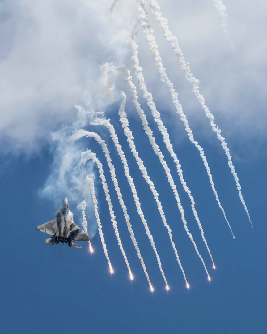 Modern fighter jet releasing flares in the sky.