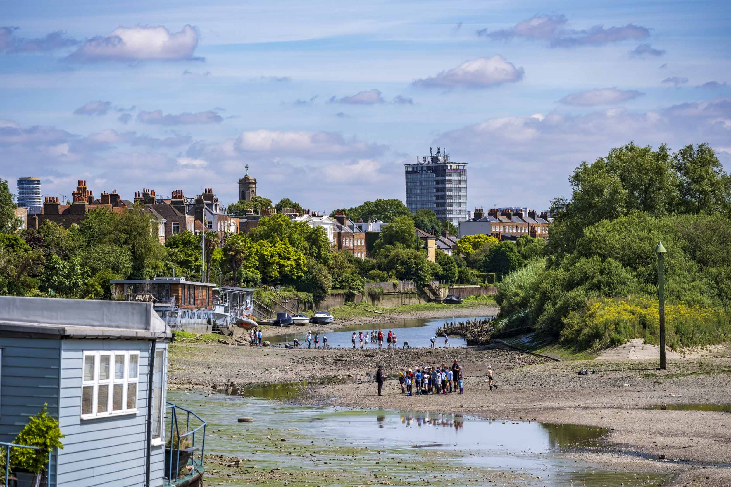 Riverside scene with groups of people learning about the river ecosystem