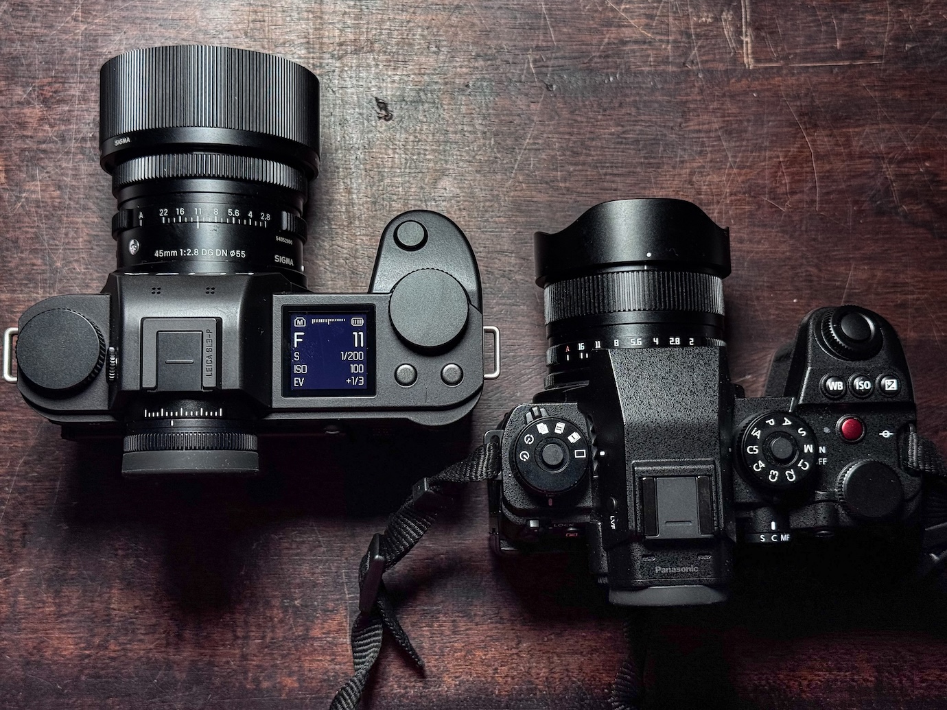 Top view of two digital cameras on a wooden surface.