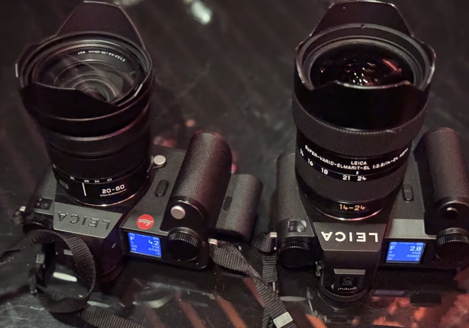 Two black digital cameras with zoom lenses.