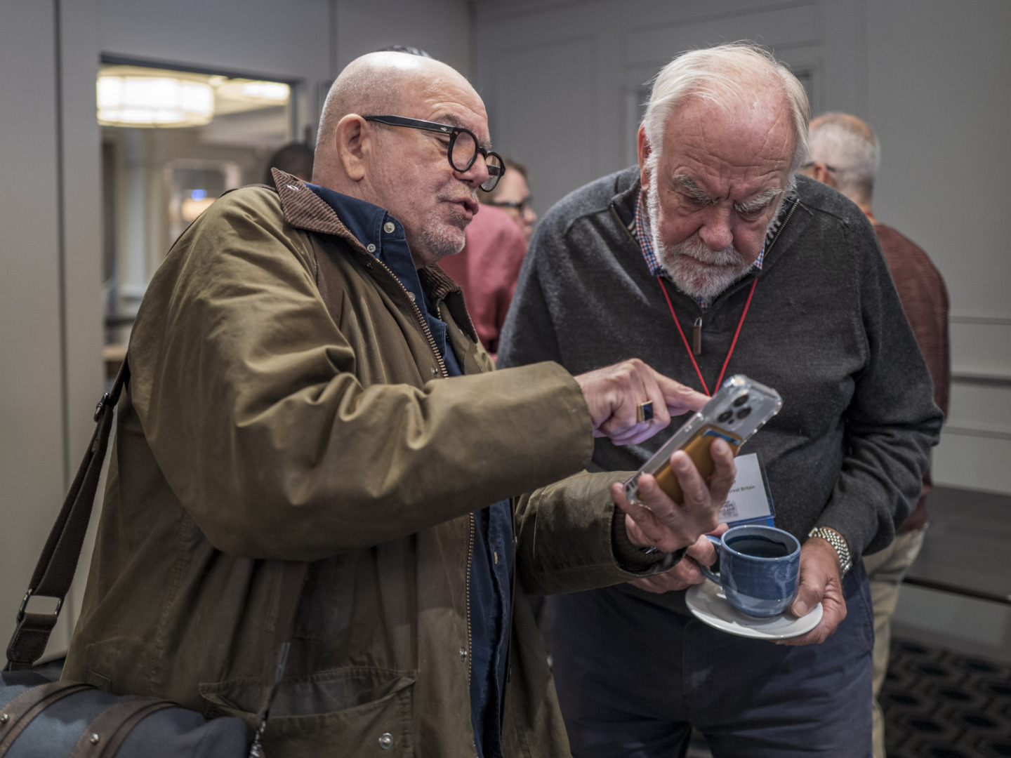 Two older men discussing something on a phone screen