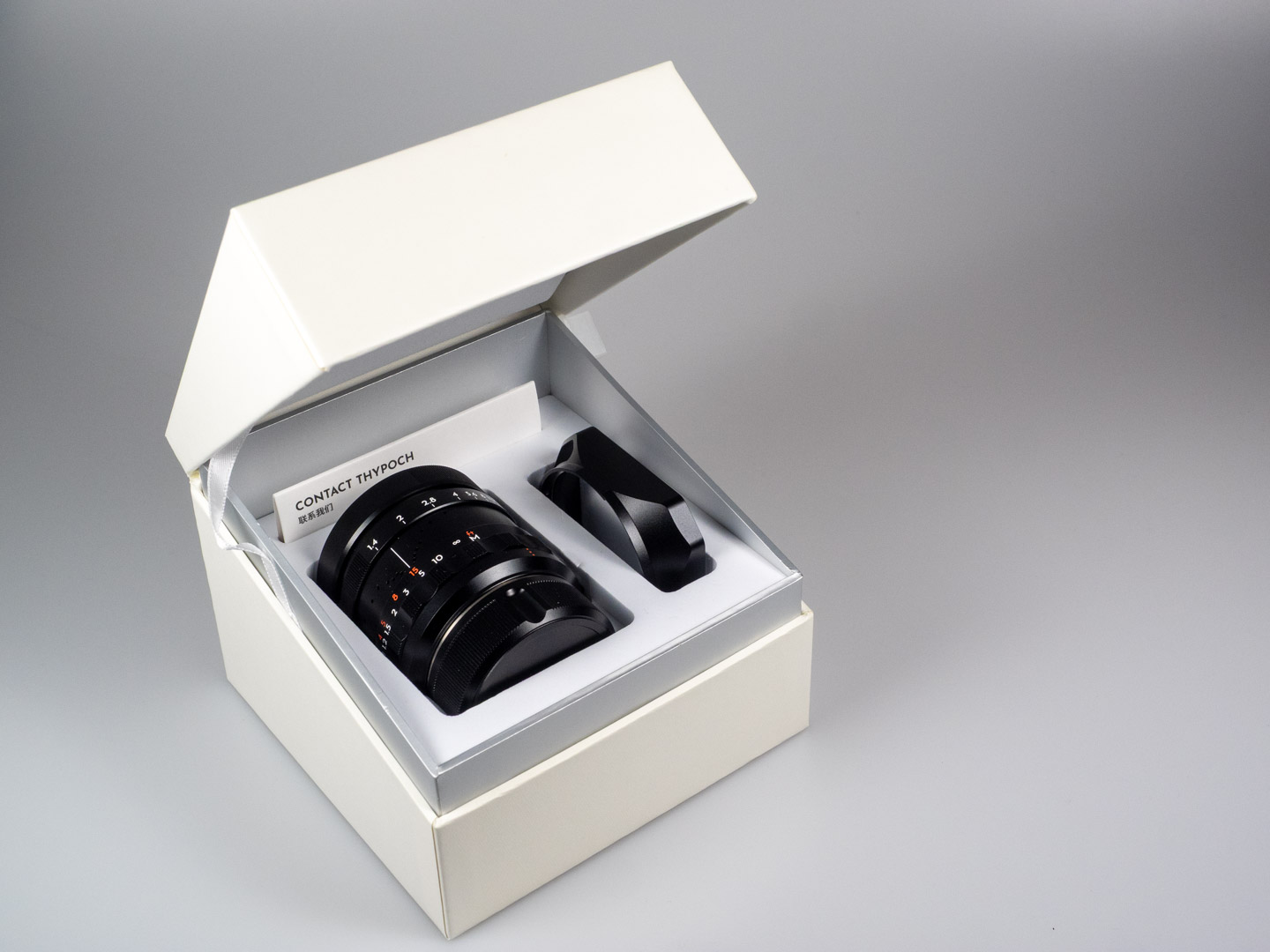 Product shot of Thypoch Simera 50/1.4: the lens and hood nestled in its presentation box.