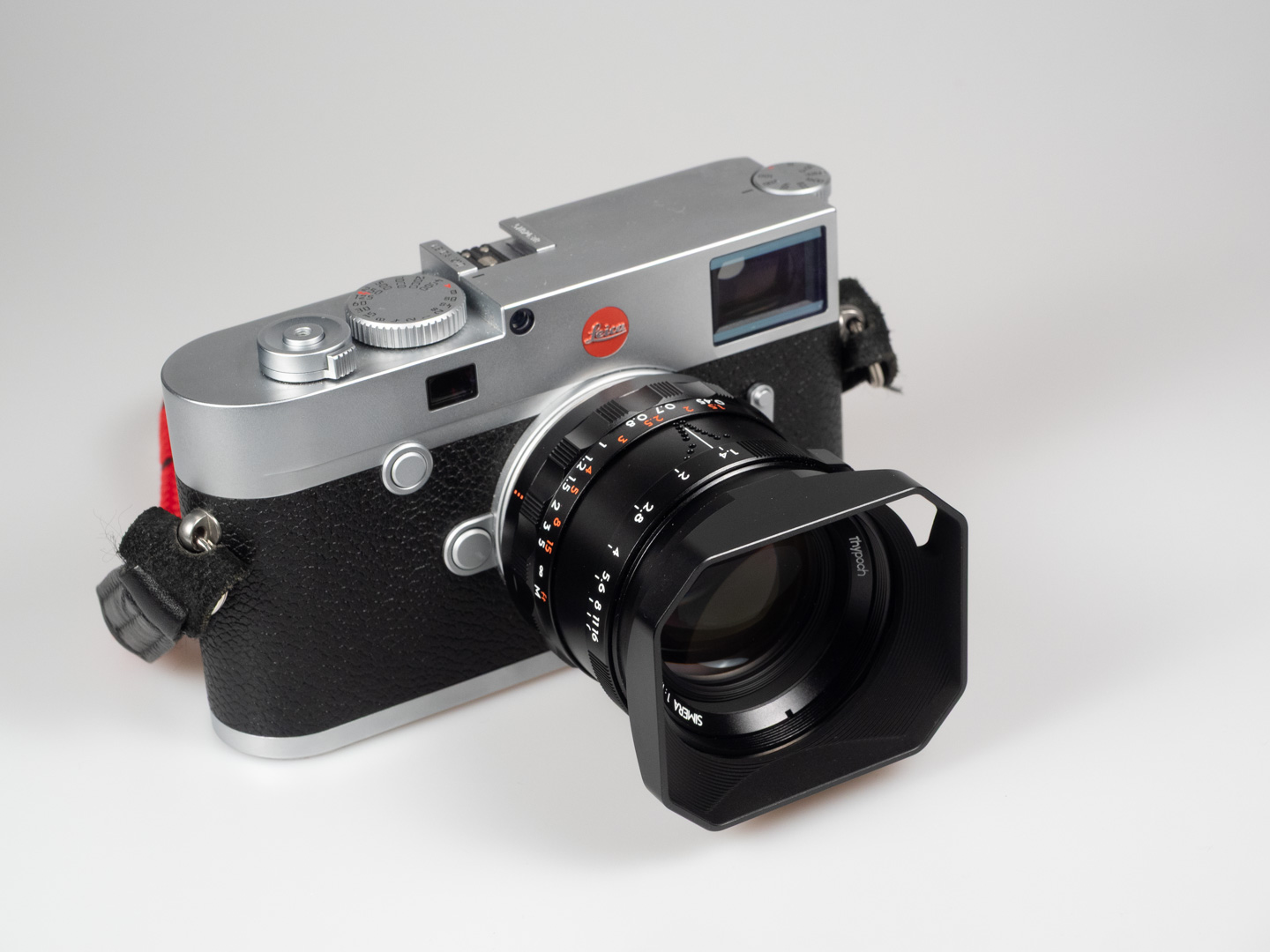 Product shot of Thypoch Simera 50/1.4: mounted on a silver Leica M rangefinder, seen from a higher angle showing the top plate.