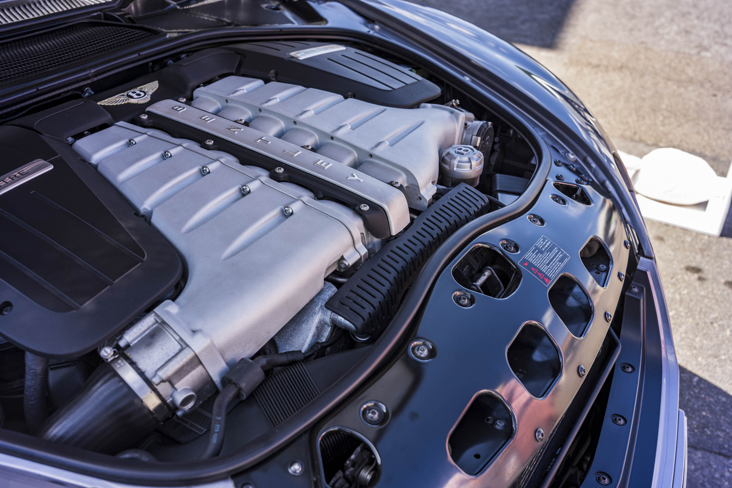 Close-up of a Bentley V8 engine bay showing the branded cam covers spelling out "BENTLEY".