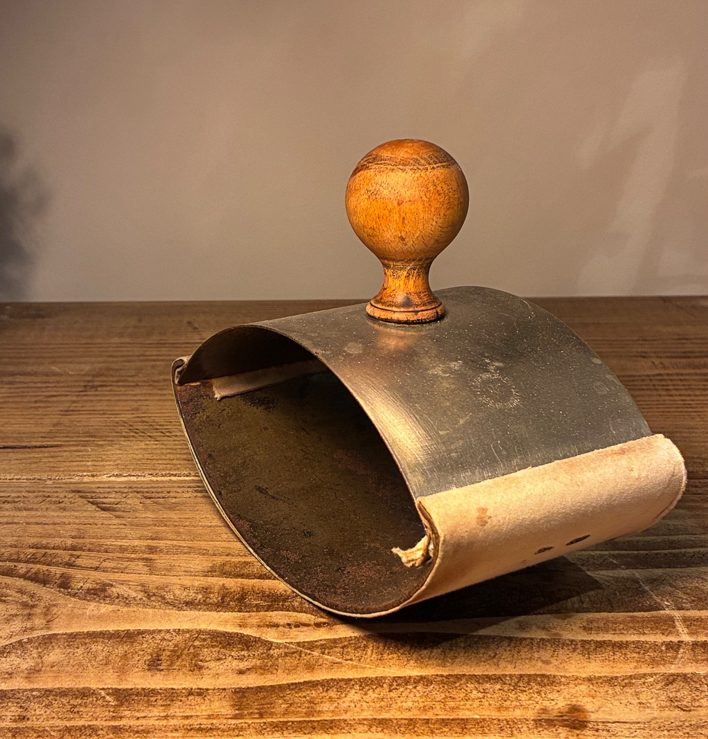 A vintage metal scoop with a wooden handle, resting on a wooden table.