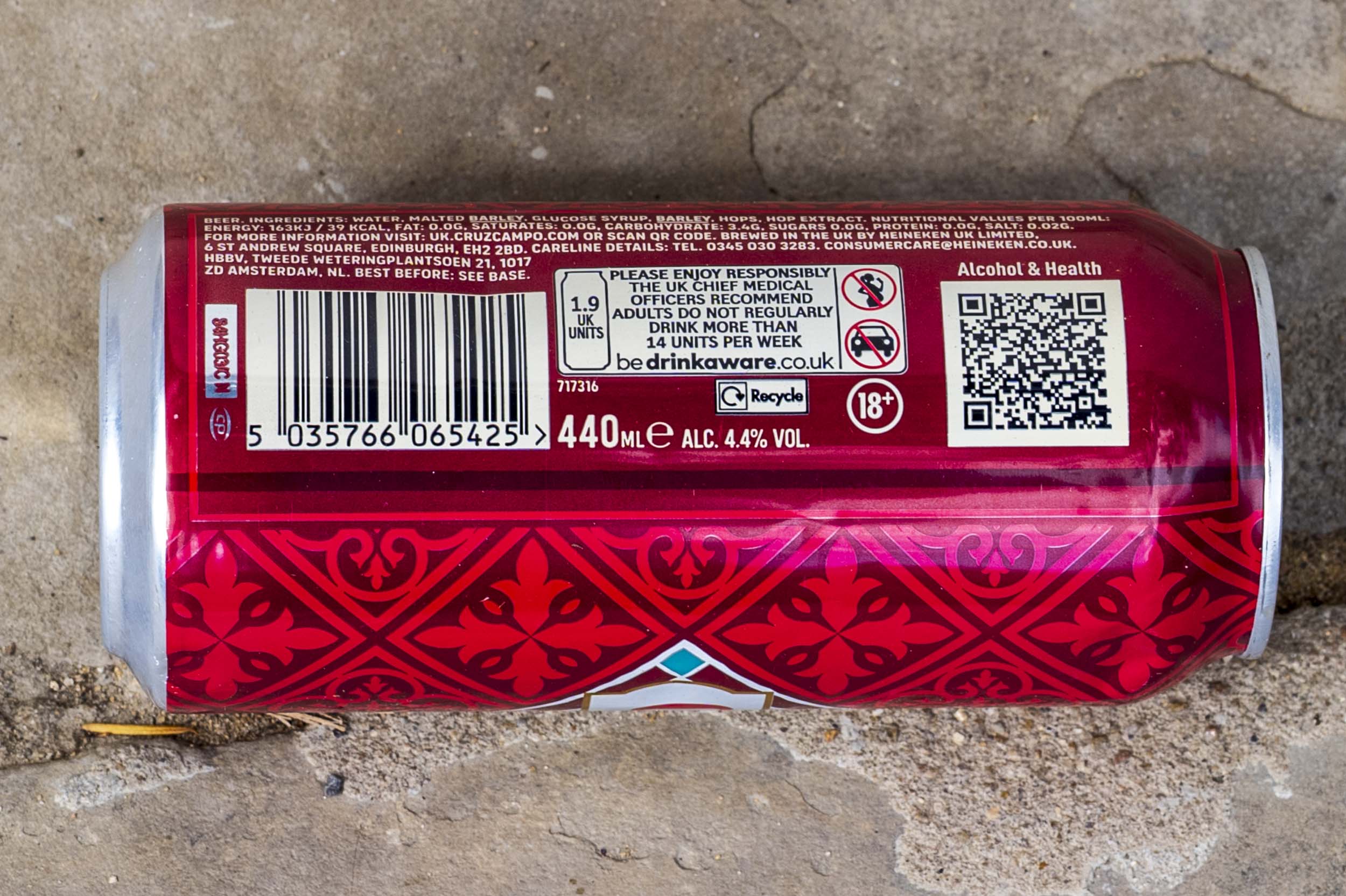 A discarded red drinks can lies on cracked paving slabs.