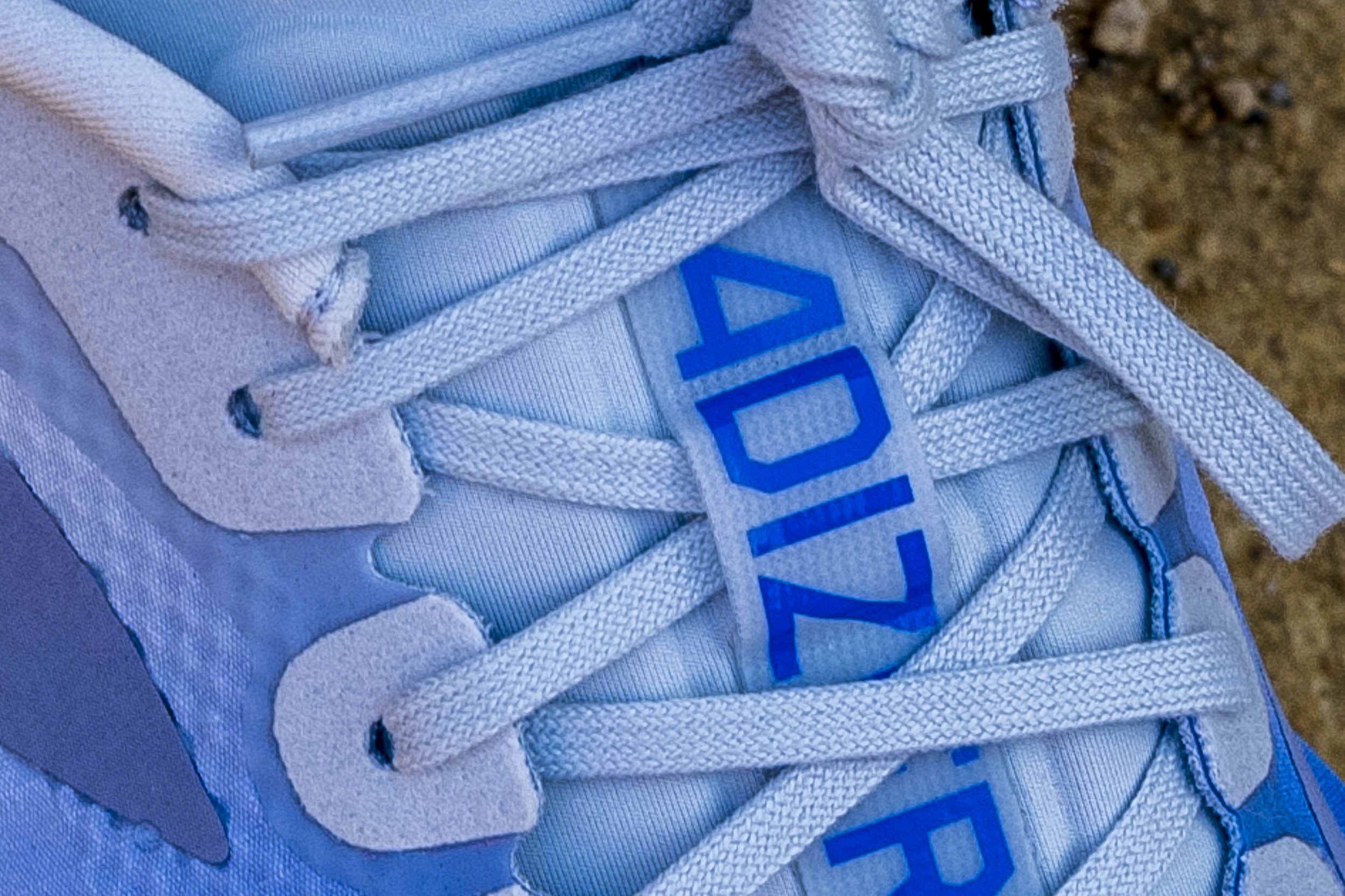 Close-up of a light blue sports shoe featuring laces and the word 'ADIZERO' prominently displayed.