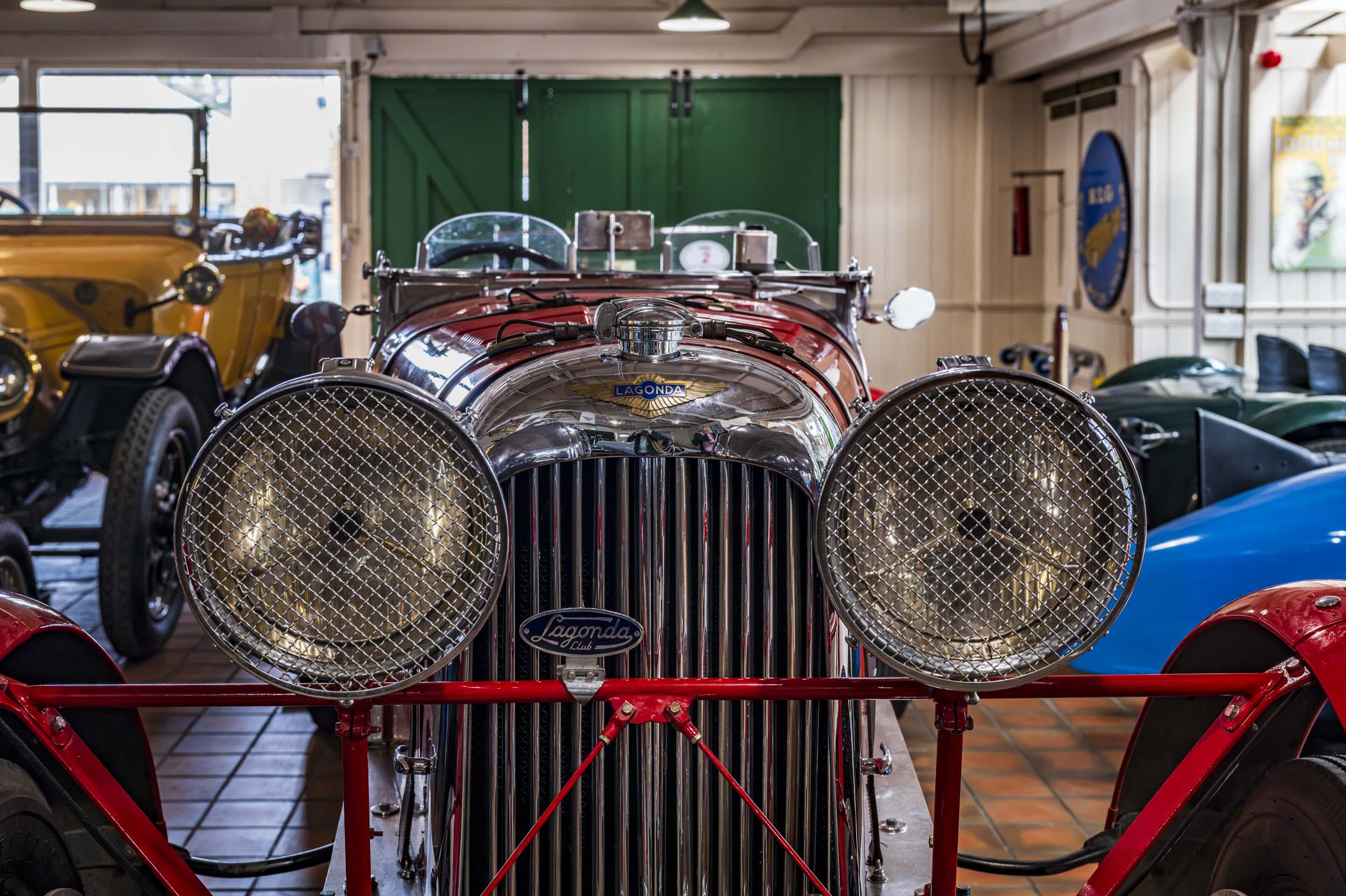 The chrome grille and mesh-covered headlamps of a vintage Lagonda car in a classic car museum garage.